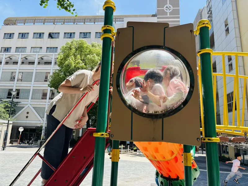 公園のドーム遊具から顔を出す子ども