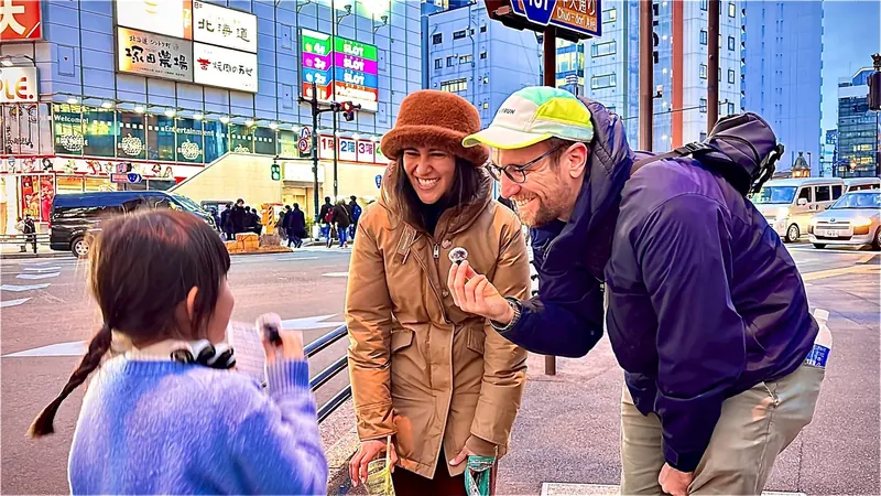 夜の街で、6歳の女の子が外国人の2人に英語でインタビューしている様子