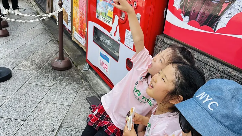自動販売機の前で英語を使う子どもたち